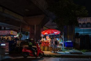 Customers buy cold drinks from a street vendor in Bangkok