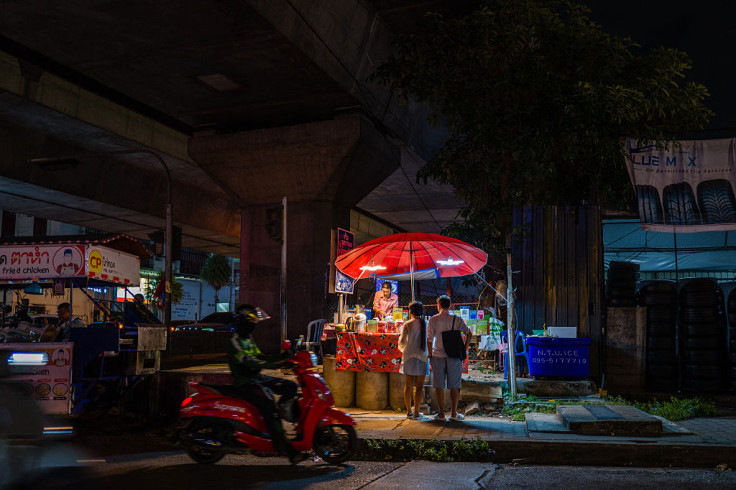 Customers buy cold drinks from a street vendor in Bangkok